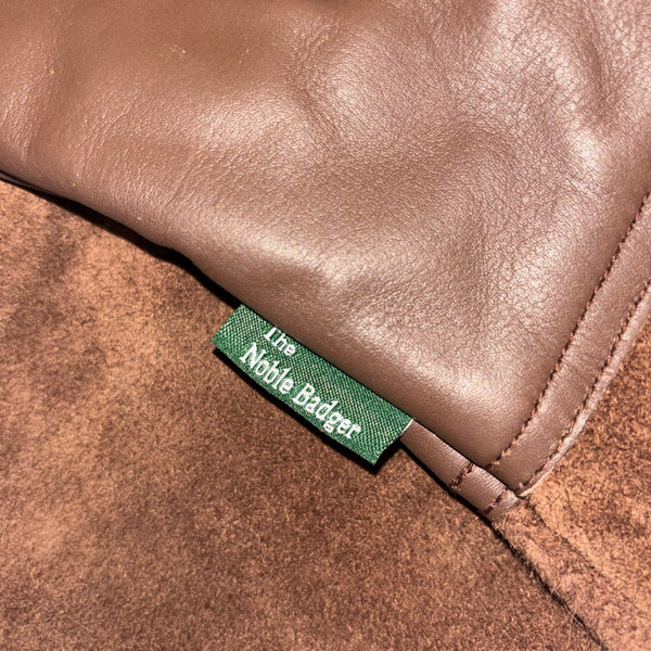 Close-up of a brown leather product with a green label featuring 'The Noble Rider' branding.
